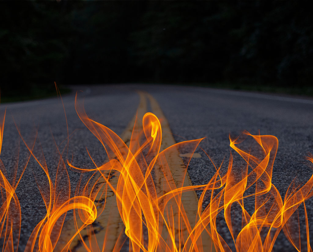 a roadway with double yellow lines and flames in the foreground