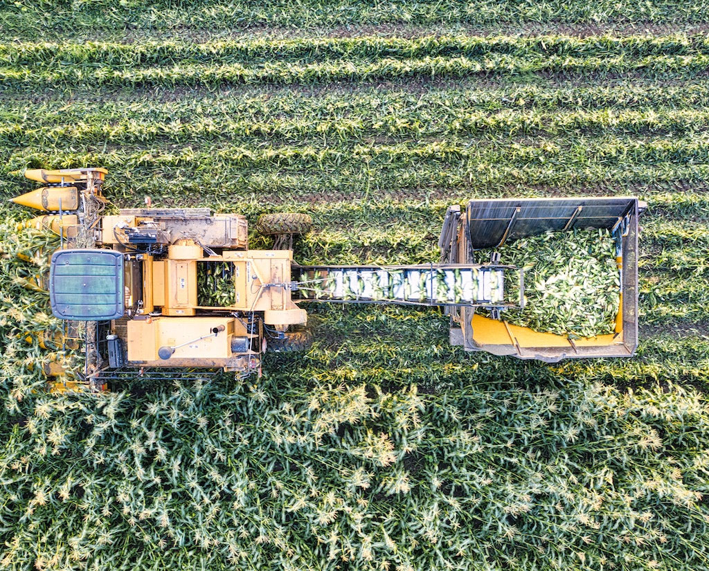 Arial view of a food tractor harvesting grains from a large field