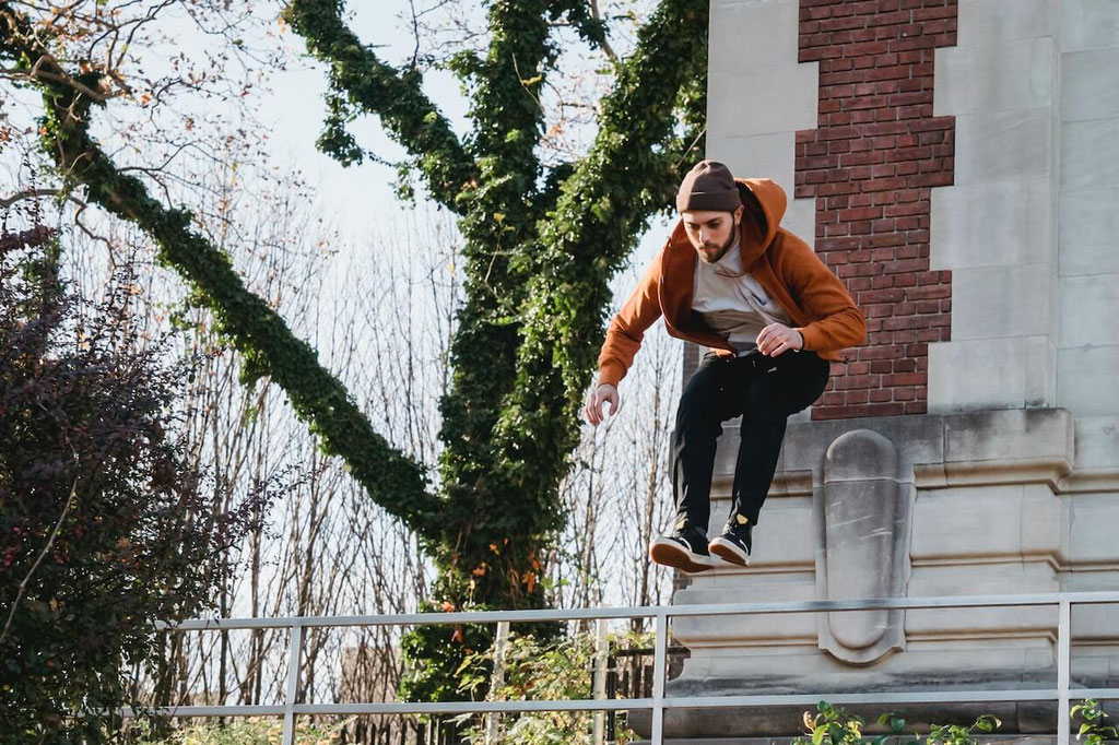 Young man in the air while jumping over a railing in front of a building